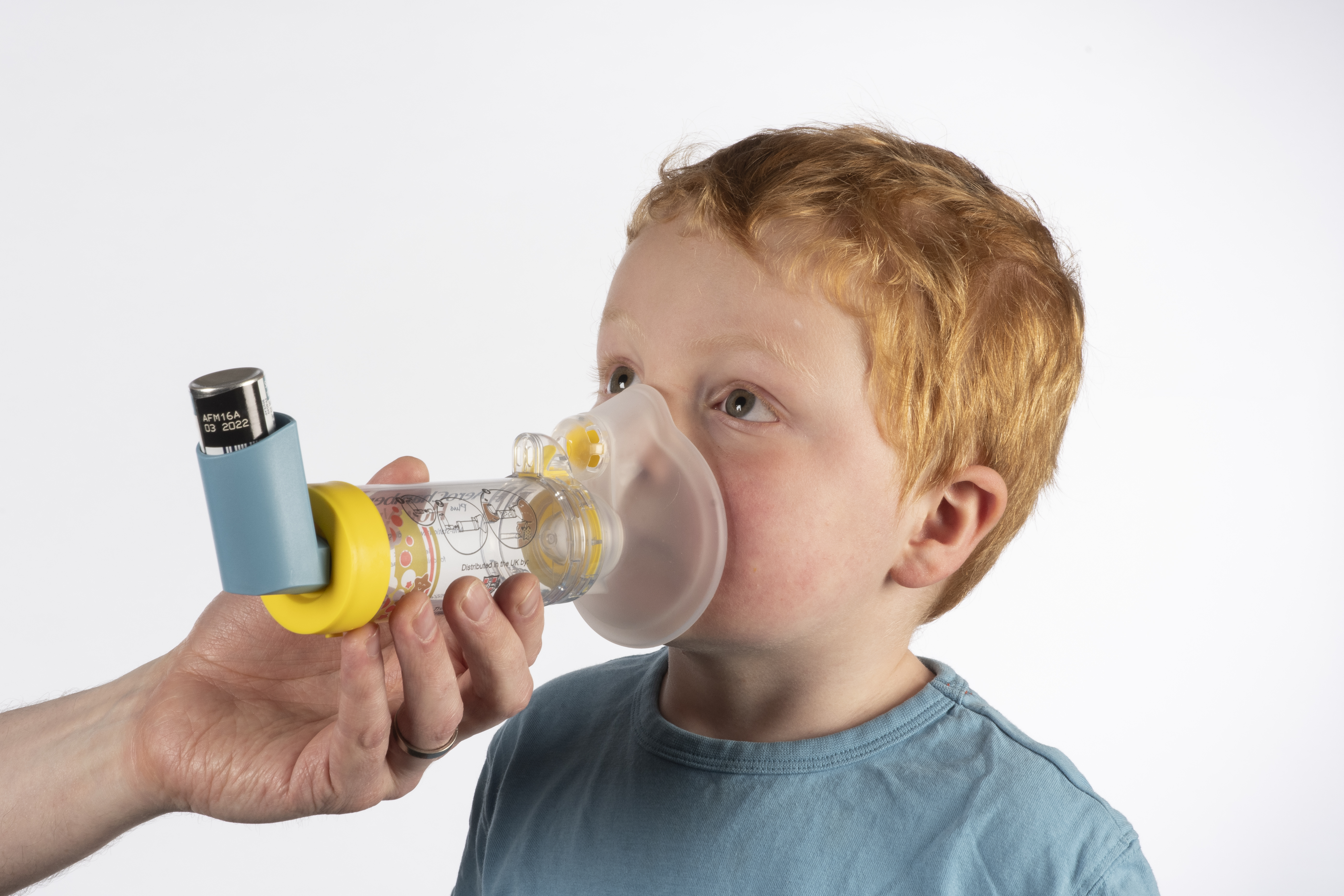 A young child using an inhaler spacer with mouthpiece.