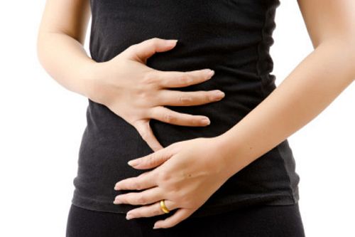 A close up image of a female's abdomen - she is is holding her hands over her stomach as though she is in pain.