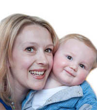 White, blonde female holding her baby boy. Both are looking towards the camera and smiling.