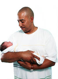 BAME male holding a new-born baby in his arms.