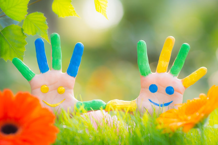 An image of two hands held up - the fingers are painted in different colours and a smiley face is painted on each palm