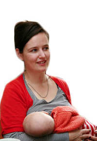 White, brunette female holding her baby to her chest whilst she breast feeds.