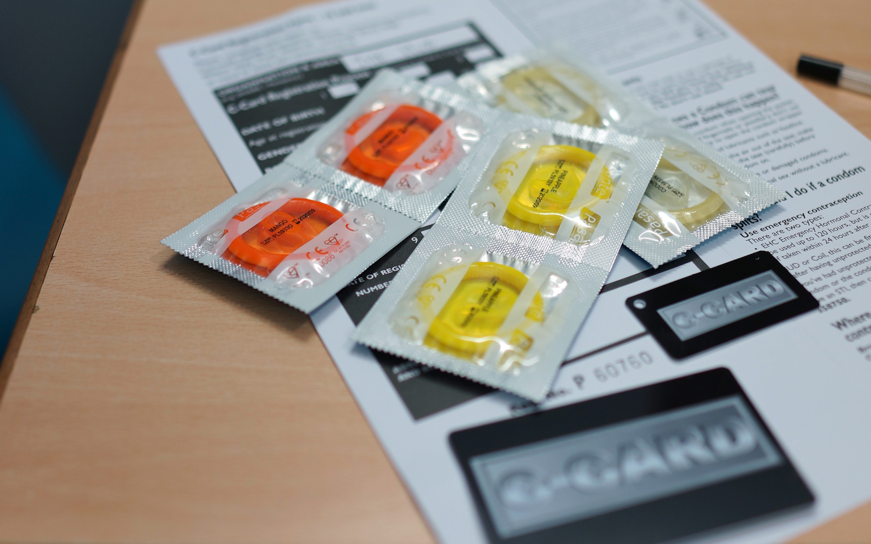 An image of a sexual health leaflet positioned on a table with multiple condoms placed out on top of the leaflet.