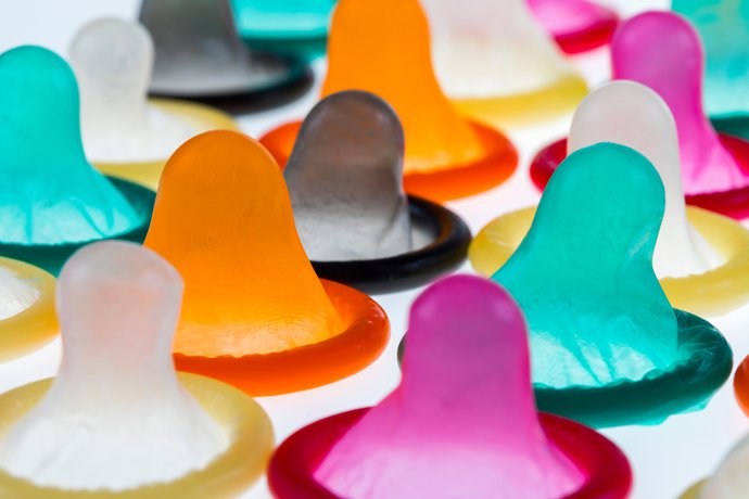 An image of lots of condoms lay out on a table. They are all different colours.