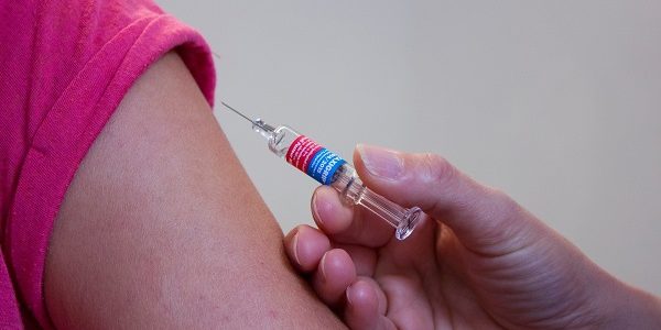 An image of a vaccine needle about to be inserted into somebody's arm.