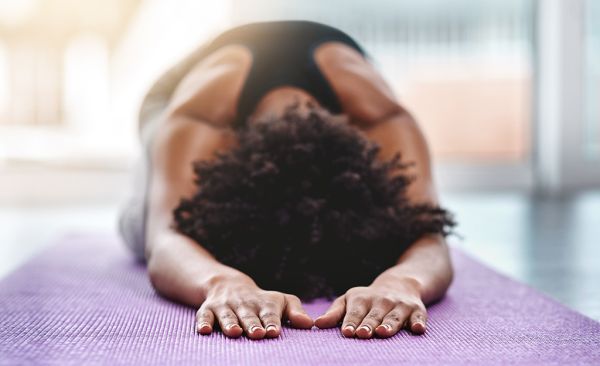 An image of a female lay down on her knees with her arms out stretched in front of her and her chest against against the floor. 